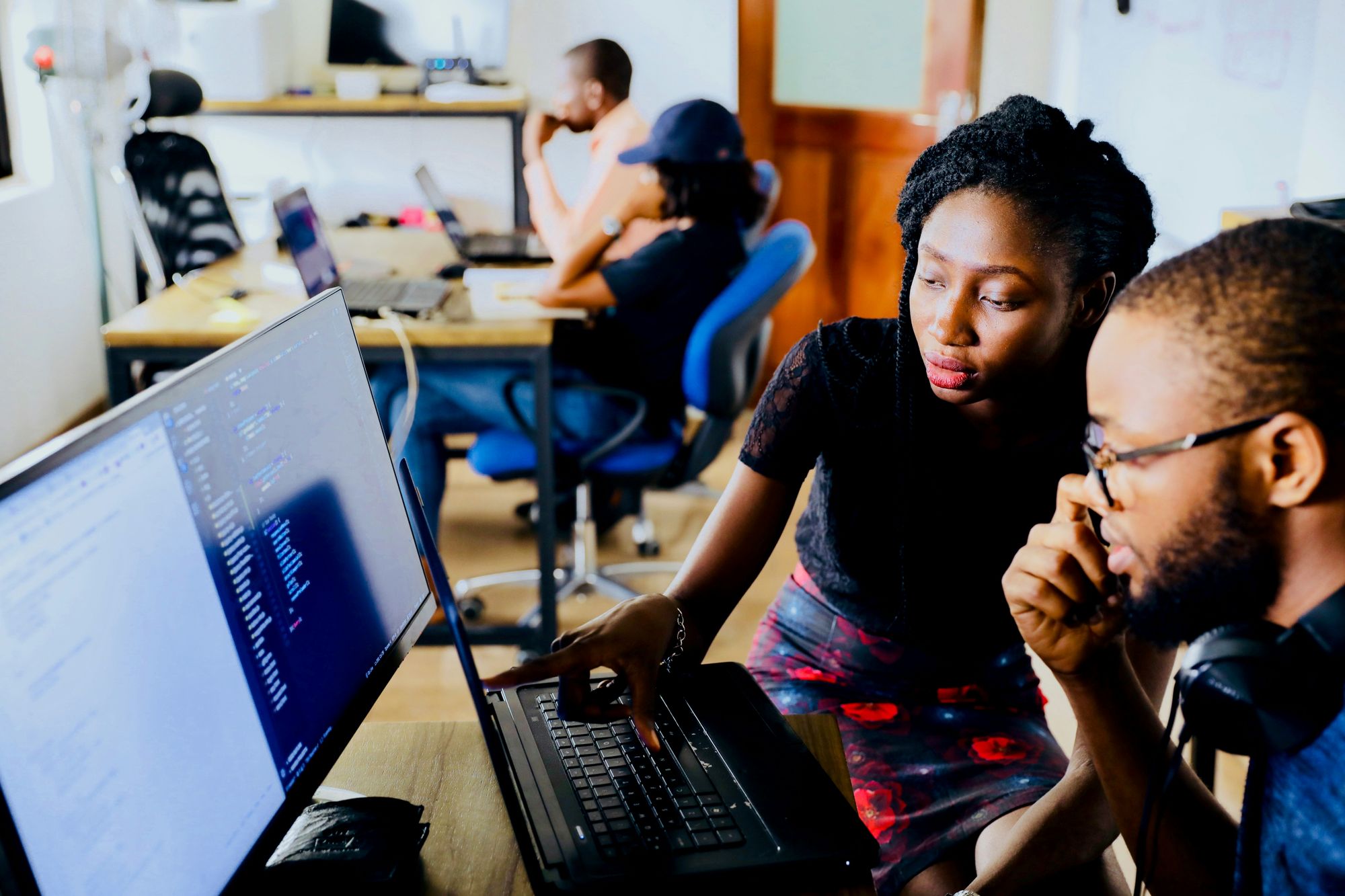 Woman showing a man some data on a computer, in an office 